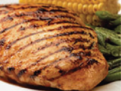 Grilled chicken on a white plate with grilled corn and grilled green beans.
